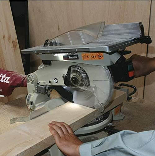 Ingletadora Makita LH1040F usando la lampara fluorescente incorporada mientras corta madera 